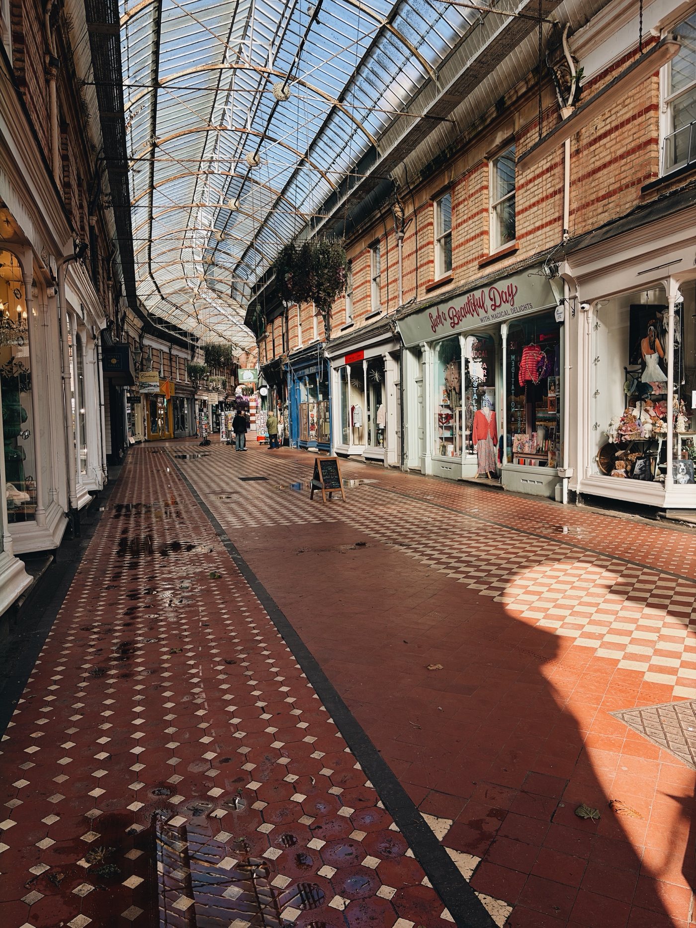 A Victorian shopping arcade with a glass roof and a red and white tiled floor