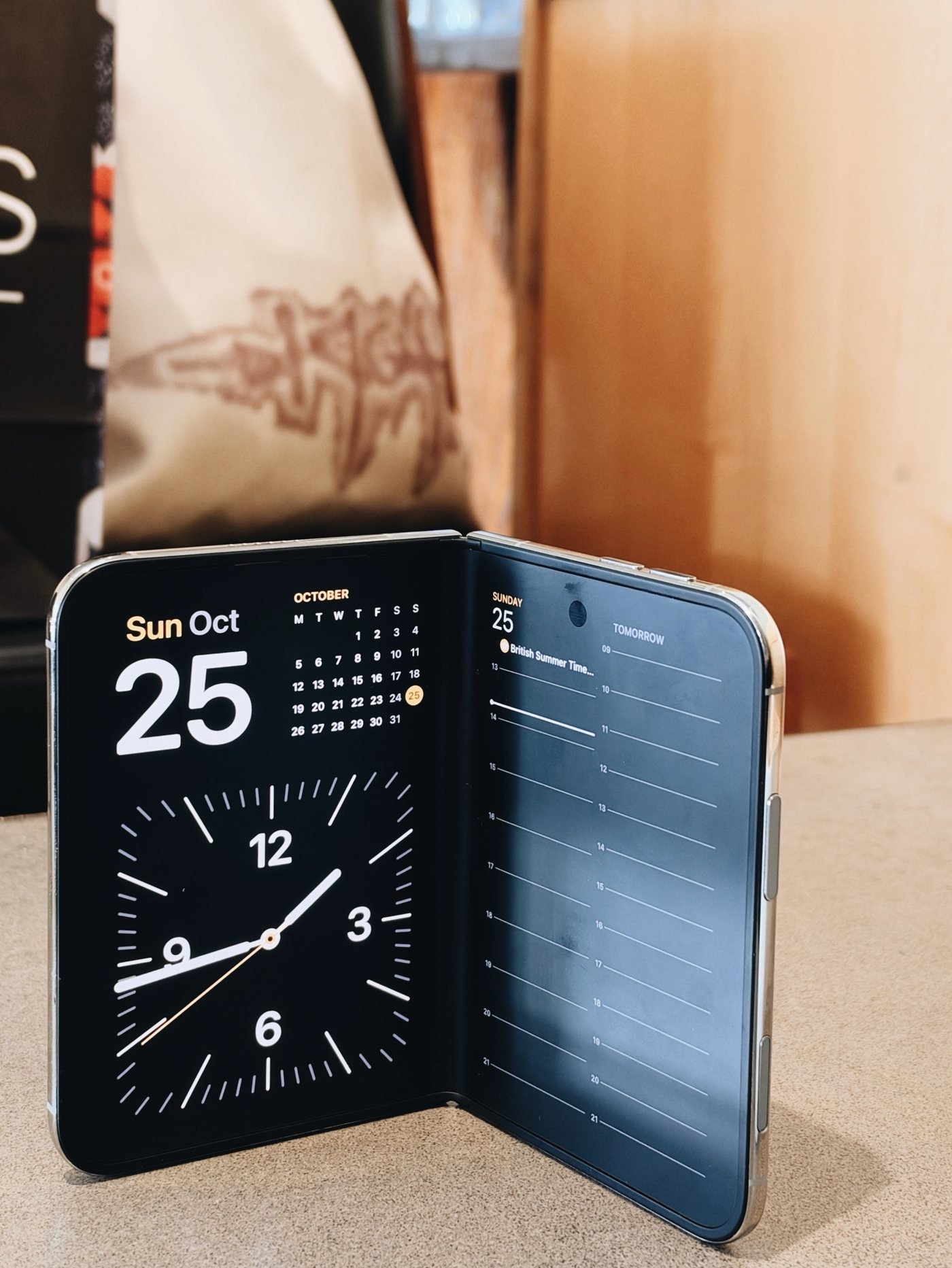 The iPhone Duo stood up half open on a worktop, showing a clock, a calendar and the day's schedule
